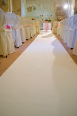 interno di chiesa addobbata con fiori e sedie bianche