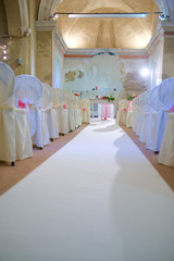 interno di chiesa addobbata con fiori e sedie bianche