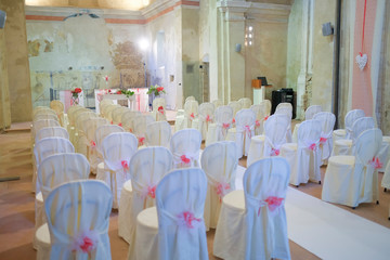 interno di chiesa addobbata con fiori e sedie bianche
