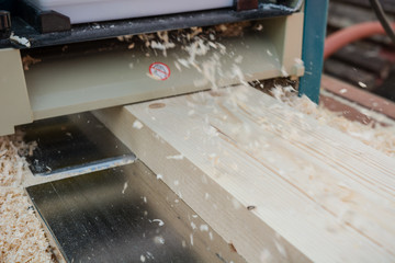 planing boards on a thicknesser. wood shavings. machine for planing wood. carpentry work. joiner's machine.