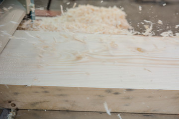 planing boards on a thicknesser. wood shavings. machine for planing wood. carpentry work. joiner's machine.