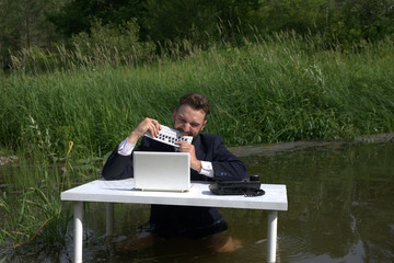 Fototapeta premium The young man is angry and bites the keyboard. Gnaws at the keyboard. nervous, tense situation in the workplace
