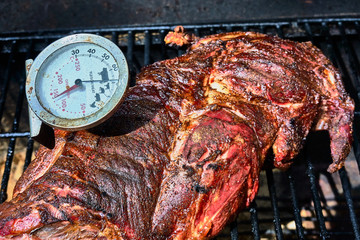 Roast lamb with inserted meat thermometer on the grill rack