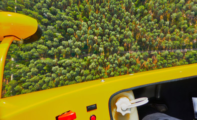 View over the outer edge of a flying ultralight aircraft to a wooded area.