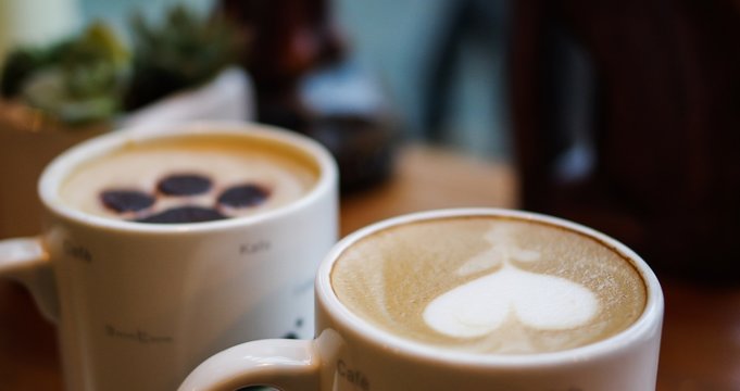 Heart shape and cat paw pattern latte art coffee in white mugs on wood table with succulent plant decoration - Powered by Adobe