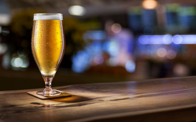 Frosty glass of light beer on the bar counter.