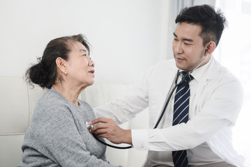 Asian doctor checking up his patient old woman in office.