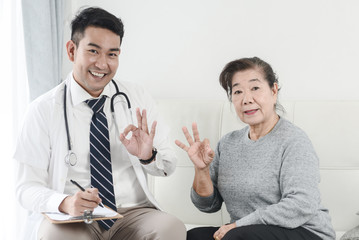 Asian doctor and senior patient with OKAY hands sign, health care concept.