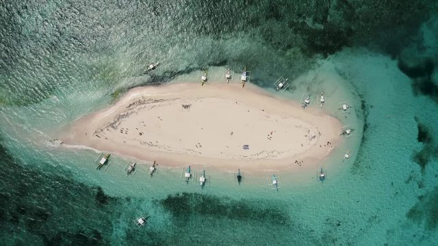 4K Aerial Drone footage of a tropical sandar in the middle of the ocean in the Philippines. The white sand beach is surrounded by beautiful aqua water and boats Naked Island Siargao