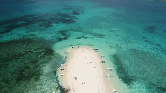 4K Aerial Drone footage of a remote sandbar in an exotic paradise with many tourists and travelers enjoying it. Surrounded by blue water and boats Naked Island Siargao Philippines