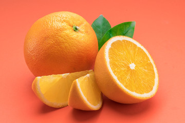Orange fruit with orange slices and leaves isolated on orange background.