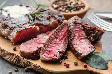Medium rare Ribeye steak with herbs and a piece of butter on the wooden tray.