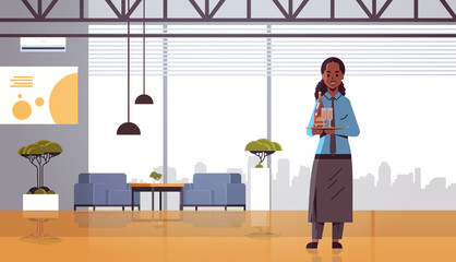 professional waitress holding bottle and glasses with champagne on tray african american woman restaurant worker in apron carrying alcohol drinks modern cafe interior flat full length horizontal