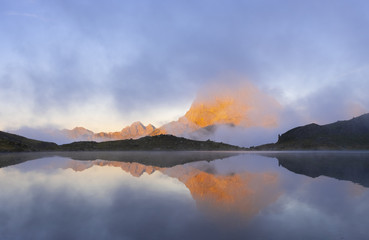 The Midi d'Ossau mountain between clouds is reflected in the gentau lake, Ayous Lakes, Pyrenees of France