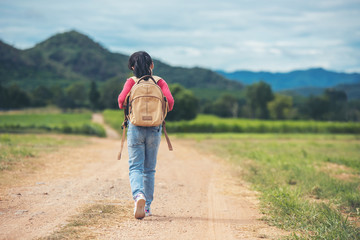 asian little girl with backpack walking at natural park outdoor