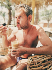 A middle aged man having coffee in a beach bar