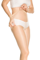 Fototapeta na wymiar Woman adjusting her nylon pantyhose on a white background