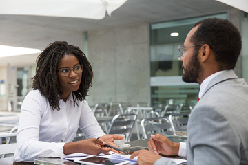Fototapeta premium Businesswoman consulting legal experts in coffee shop. Business man and woman meeting in street cafe, talking and smiling. Business discussion concept