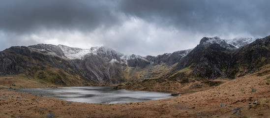 Beautiful moody Winter landscape image of Llyn Idwal and snowcapped Glyders Mountain Range in Snowdonia