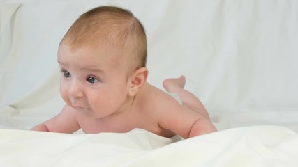 Portrait of beautiful funny little newborn baby of two months lying on a white bed