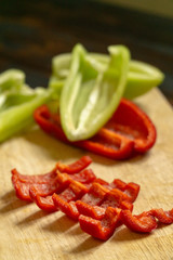Sliced red and green bell peppers on a wooden cutting board. Organic food and coocking.