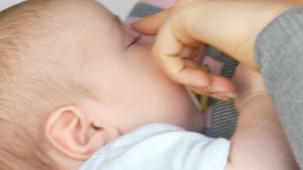 Young beautiful mother with long dark hair is holding a newborn infant baby of two months on a white background in studio