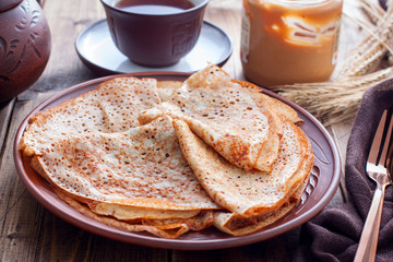 Openwork pancakes on a clay plate, selective focus