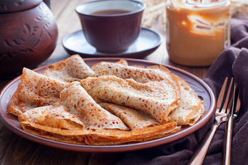 Openwork pancakes on a clay plate, selective focus