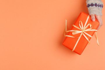 Woman hands holding gift box on orange background