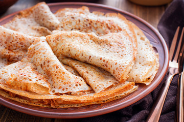 Openwork pancakes on a clay plate, selective focus