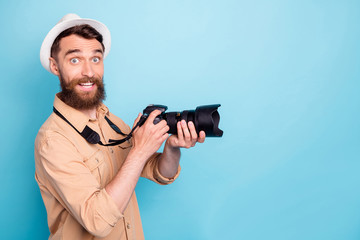 Profile side photo of charming man holding camera smiling wearing brown shirt isolated over blue background