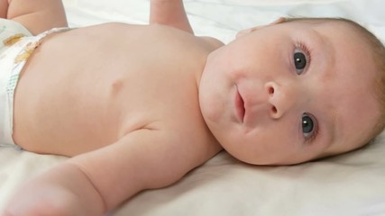 Portrait of beautiful funny little newborn baby of two months lying on a white bed
