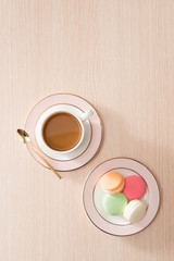 Cup of coffee with macaroons on wooden background