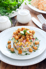 Salad with smoked sausage and crackers on a white plate in a portion serving, selective focus