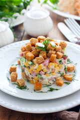Salad with smoked sausage and crackers on a white plate in a portion serving, selective focus