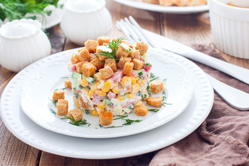 Salad with smoked sausage and crackers on a white plate in a portion serving, horizontal