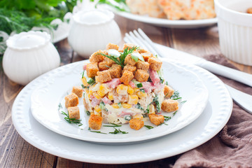 Salad with smoked sausage and crackers on a white plate in a portion serving, horizontal