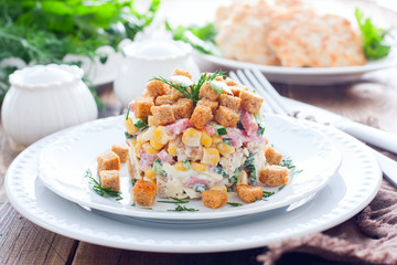 Salad with smoked sausage and crackers on a white plate in a portion serving, horizontal