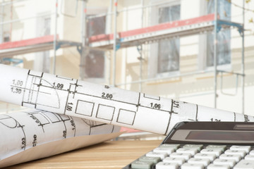 Baustelle für ein Haus, Taschenrechner und Baupläne