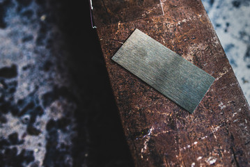 The rectangular stainless steel sheet was created to be used as a name tag, placed on a rusted metal.