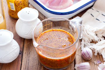 Honey mustard marinade in a transparent glass on a wooden table, selective focus