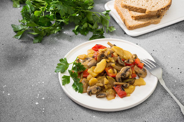 Stewed vegetables in a white plate on a gray table. Healthy diet. Vegetarian food