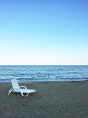 A lonely plastic lounge chair at the beach with seascape