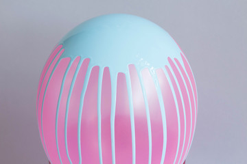Pink balloon with blue dripping paint on grey background