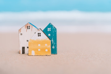 Small home model on sand beach with blue sky background.