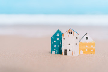 Small home model on sand beach with blue sky background.