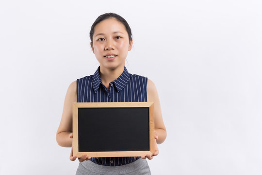 Portrait of a playful red hair business woman holding a shalk board over white wall background.