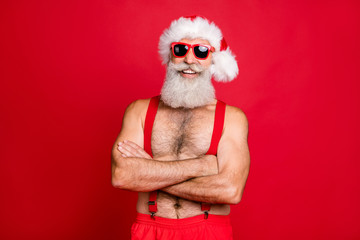 Portrait of his he nice attractive content cheerful cheery funky glad gray-haired muscular macho St Saint Nicholas folded arms wintertime isolated over bright vivid shine red background