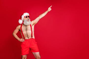 Fototapeta na wymiar Portrait of his he nice attractive cool cheerful cheery funky positive playful gray-haired man having fun St Saint Nicholas holly jolly pointing finger up isolated on bright vivid shine red background
