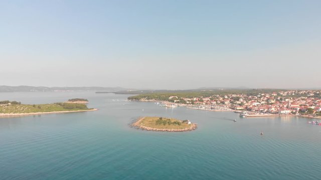 a professional looking aerial of the crystal clear adriatic sea in the mediterranean, flying towards a small town called pakostane, showing the beautiful land- and seascape with islands and marina